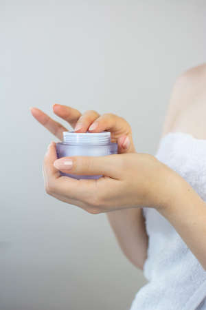 Woman's hands holding a bottle of cream to apply to her faceの写真素材