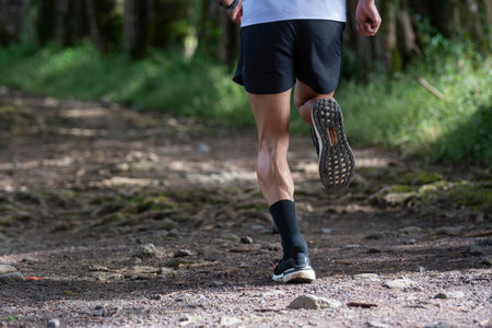 Muscular legs of a man running in the middle of the forest