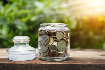 Coins in the bottle for finance on wooden wooden table with green nature background, Saving conceptの写真素材