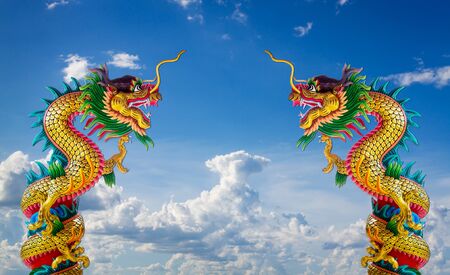 Twin golden chinese dragon statue in blue sky backgroundの写真素材