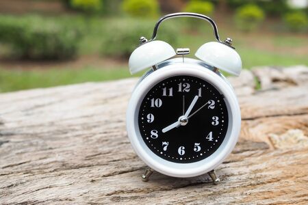Retro alarm clock on old wooden table with green blurred background. vintageの写真素材