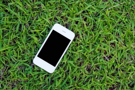 Mobile smart phones on green grass background. top viewの写真素材