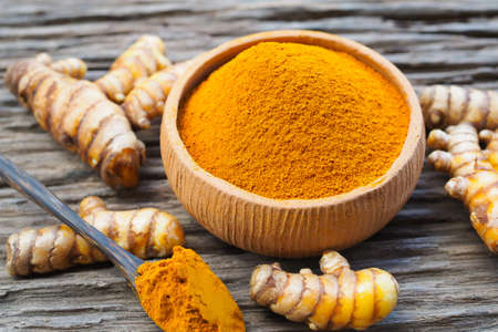 Turmeric powder in bowls and fresh turmeric on old wooden background. Herbsの写真素材
