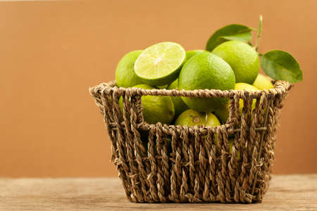 Fresh green lemon in basket on brown background, limeの写真素材
