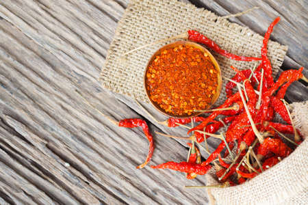 Cayenne pepper and dried chilli with sack on wooden table, selective focusの写真素材