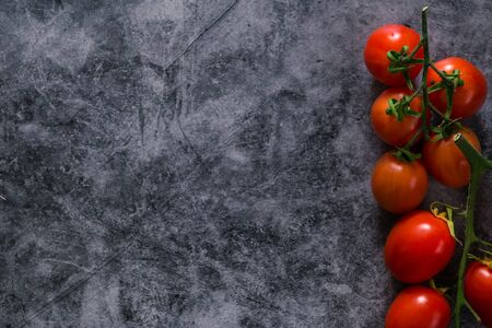 fresh tasty cherry tomatoes on dark stone background with copy space