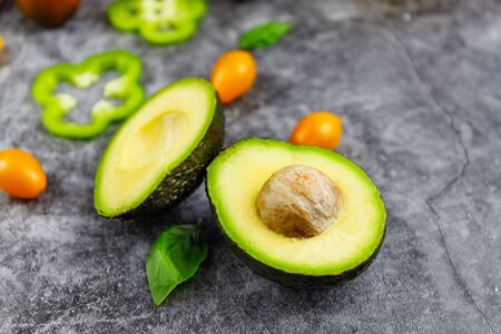 Avocado halves with lime slices and baby spinach leaves on a grey concrete, stone o background. Top...