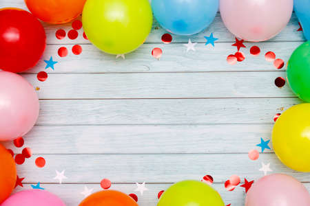 Colorful balloons and confetti on wooden table top view. Festive or party background. Flat lay style. Birthday greeting card. Carnival.の写真素材