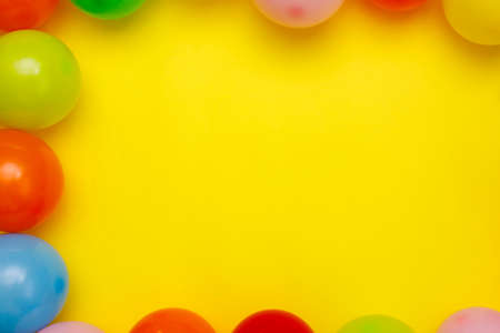 Colorful balloons and confetti on yellow table top view. Festive or party background. Flat lay style. Birthday greeting card. Carnival.の写真素材