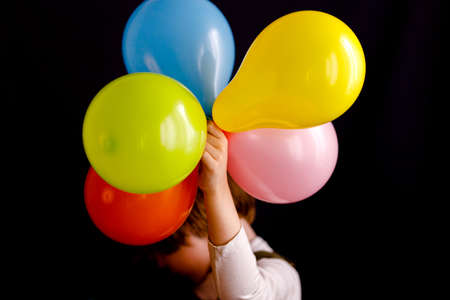 Kid with colorful balloons on black backgroundの写真素材