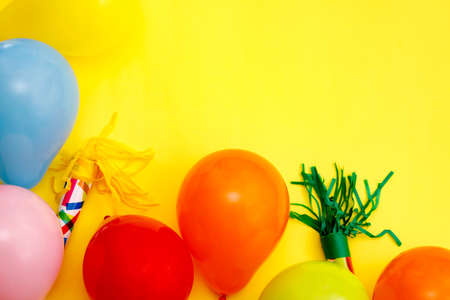 Colorful balloons and confetti on yellow table top view. Festive or party background. Flat lay style. Birthday greeting card. Carnival.の写真素材