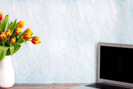 Office or home workspace with bouquet of colorful tulips on the table. Feminine workspaceの写真素材