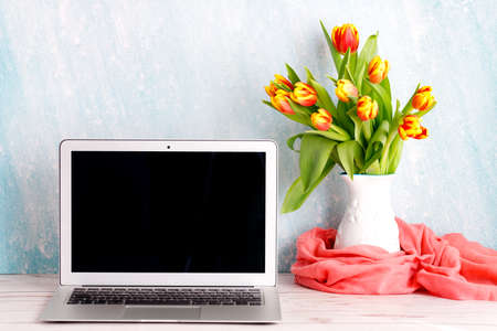 Office or home workspace with bouquet of colorful tulips on the table. Feminine workspaceの写真素材