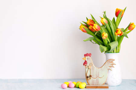 Bouquet of yellow fresh tulips in white jug with painted Easter eggs on white background.の写真素材