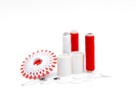 Sewing supplies on a white wooden table: sewing thread, scissors, a large spool of thread, pieces of cloth, needles, centimeter, buttonsの写真素材