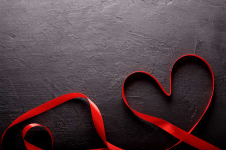 Happy Valentines Day. Red Ribbon on black stone background. Valentines Day conceptの写真素材