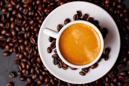 Hot fresh black coffee with milk foam for morning menu in white ceramic cup with coffee beans...