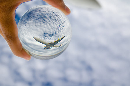 Airplane flying on cloudy sky photography in clear crystal glass ball.の写真素材