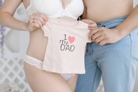 Future parents know sex of their baby, holding clothes for their future baby, pregnancy concept.の写真素材