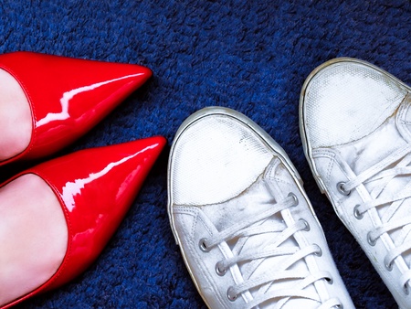 Red high heels and white sneakers on blue carpet, different fashion stylesの写真素材
