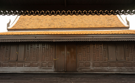 A large wooden Thai house in dark brown color with a typical clay roof and good designedの写真素材