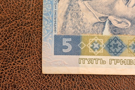 KIEV, UKRAINE - DECEMBER 19, 2014: Ukrainian paper money, hryvnia, lays down on brown imitation leather with patterns. Partial macro photo of the corner of the banknote. Bill of fiveのeditorial素材