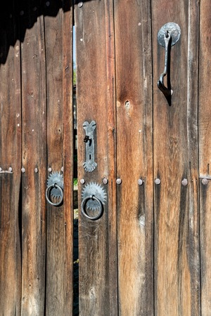 Close up of old double wooden tiled rustic house door to the street in Bulgaria, Rhodope mountain. Decorated with metallic hoops and handles.の写真素材