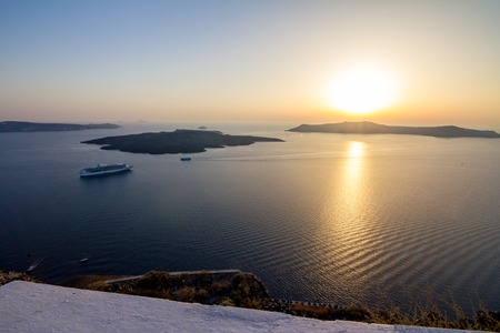 Elevated incredibly romantic sunset scene on Santorini. Fira, Greece, from above. Amazing golden hour view from public path walk towards volcano in the center of the caldera. Shortly before the sunsetの写真素材