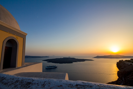 Elevated incredibly romantic sunset scene on Santorini. Fira, Greece, from above. Amazing golden hour view from public path walk towards volcano in the center of the caldera. Shortly before the sunsetの写真素材