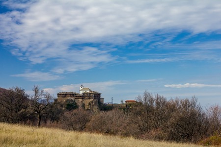 Autumn landscape with Glozhene Monastery St. George from far away. This is 13th century old stone and wooden building in Bulgaria. Orthodox monastery in Stara Planina mountainの写真素材