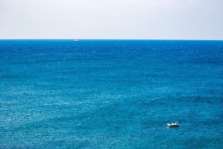 Two boats in the blue waters of Adriatic Sea in a clear but windy spring day, focus on the back boat. Calm scene, crystal backgroundの写真素材