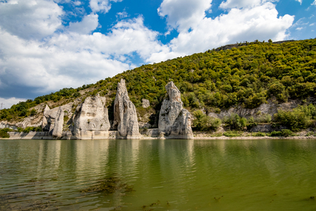 Autumn landscape at the Chudnite Skali natural phenomenon, a.k.a Wonderful Cliffs, Bulgaria, scenery cloudy sky with white clouds, green water with rocks refection and still green mountain hillsの写真素材