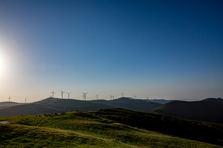 Landscape view with wind turbines and Sun, Buzludzha peak, Stara Planina mountain, Bulgaria, early spring morning with clear blue sky and green grass.の写真素材