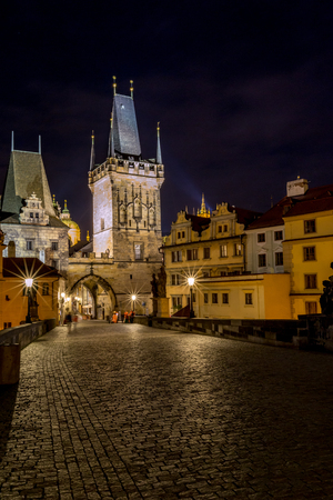 Long exposure night photo with beautiful street lamps from Charles Bridge, Prague towards the Lesser Town Bridge Tower on the west bank of Vltava river. Blurred silhouettesの写真素材
