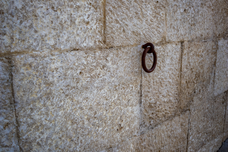 Rusty iron hoop hanging from carved stone wall in Matera, Basilicata region in Italyの写真素材