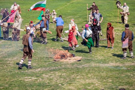 VARVARA, BULGARIA - MARCH 24, 2019: Moment from National Festival Dervish Varvara presents traditions of Bulgarian Kuker Games. Jumping over burning straw pile bonfire as part of keeping the ritualのeditorial素材