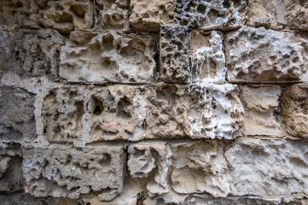 Ancient pastel warm colors stone wall with bricks eaten by the rain and time, background or...