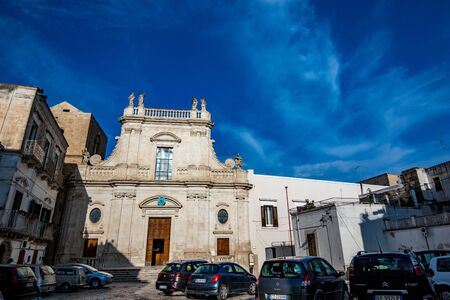 CASTELLANETA, ITALY - AUGUST 27, 2018 - Public square is empty and only cars parked in front of Cathedral of St. Nicola in normal Monday afternoon. Puglia region. Southern Italyのeditorial素材