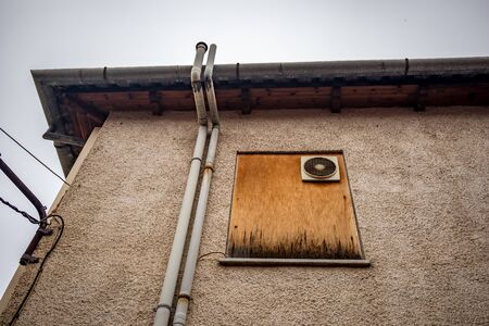 Chipboard wood covered window with old big windowed electrical fan on the back side of a city building, Ioannina downtown, Greeceの写真素材