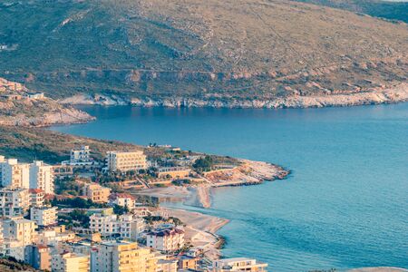 Golden hour landscape and cityscape from Lekuresi Castle, Saranda, Albania with Adriatic Sea coast and residential district view, clear spring sky with evening hazeの写真素材