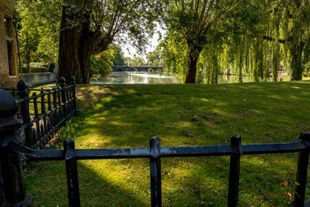 Shadows and grass view of beautiful historic city center park with lake and bridge, architecture of Bruges or Brugge, West Flanders province, Belgium. Lovely summer August weatherの写真素材