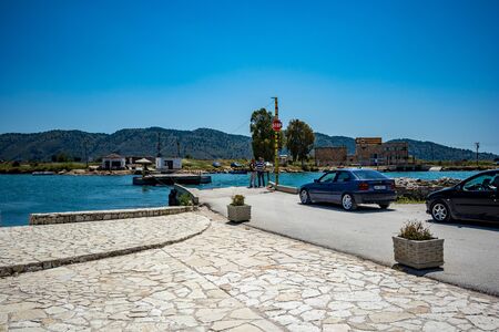 BUTRINT, ALBANIA - JUNE 7, 2019: Two Albanians wait next to their cars for the small old river ferry...