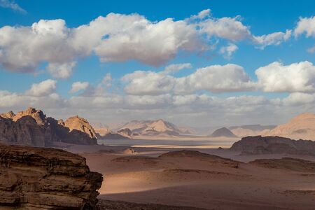 Kingdom of Jordan, Wadi Rum desert, sunny winter day scenery landscape with white puffy clouds and warm colors. Lovely travel photography. Beautiful desert could be explored on safari. Colorful imageの写真素材