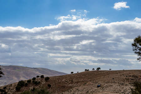 Minimalistic view, landscape, Promised Land hill as seen from Mount Nebo, Kingdom of Jordan, Middle East, beautiful clouds in windy winter afternoonの写真素材