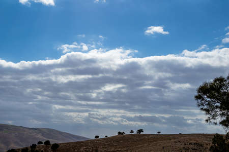 Minimalistic view, landscape, Promised Land hill as seen from Mount Nebo, Kingdom of Jordan, Middle East, beautiful clouds in windy winter afternoonの写真素材
