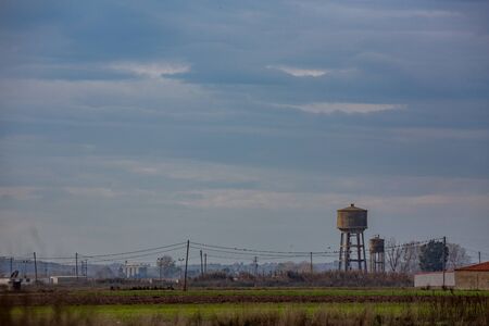 Hazy midday hot daytime landscape from far away with haze of village of Nea Kessani, Xanthi region, Northern Greece with water tower and industrial zoneの写真素材