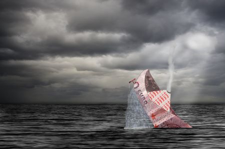 ten euro bank note folded to a ship sinks at storm in the seaの写真素材