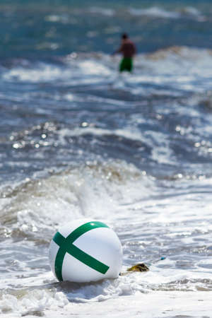 waves on a shore with buoy and single personの写真素材