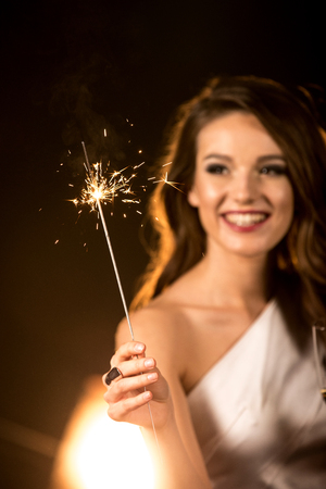 Beautiful brunette woman holding sparkler and celebratingの写真素材