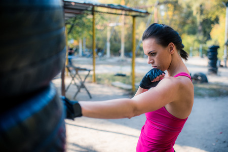 Woman boxer doing cross kick working out outdoors.の写真素材